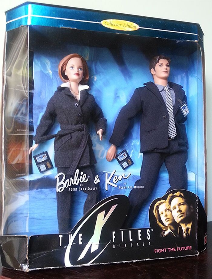 Barbie and Ken dolls dressed as FBI Agents Dana Scully and Fox Mulder, in a box decorated with X Files imagery